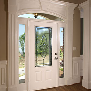 Front door on the inside of a home with a glass window and two narrow, tall windows on either side